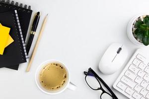 top view of modern white office desk with computer keyboard, blank notebook page and other equipment on white background. Workspace concept, workspace management style, business design space with copy photo
