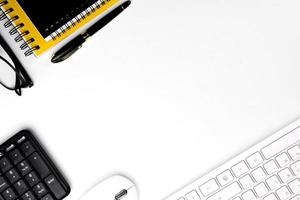 top view of modern white office desk with computer keyboard, blank notebook page and other equipment on white background. Workspace concept, workspace management style, business design space with copy photo