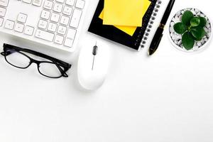 top view of modern white office desk with computer keyboard, blank notebook page and other equipment on white background. Workspace concept, workspace management style, business design space with copy photo