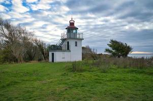 Lighthouse, Spodsbjerg Fyr in Huntsted on the coast of Denmark. Sun rays shining photo