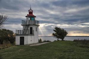 Lighthouse, Spodsbjerg Fyr in Huntsted on the coast of Denmark. Sun rays shining photo