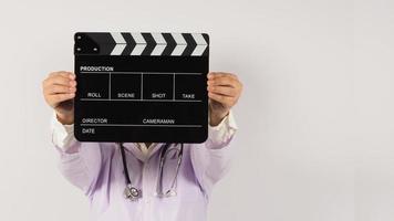 Doctor's holding Black Clapper board in hand on white background. Studio shooting. photo