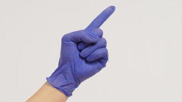 Close up of Hand is doing point finger hand sign on white background. Hand wear violet or purple latex glove. photo