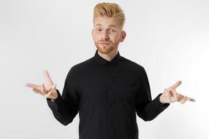 Confused guy in black shirt isolated. Young man doesn't know what to choose. Male make a decision concept. Copy space. Caucasian Redheaded man with styled red beard and hairstyle. Handsome guy photo