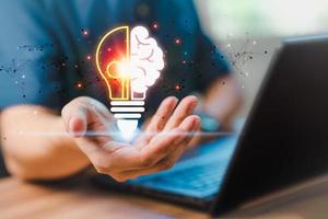 Man holding abstract light bulb icon while working on computer thinking and create new ideas, with technological innovation and creativity Ideas inspired by online technology innovation. photo