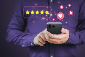 Man hand using a mobile phone with popup five star icon for feedback review satisfaction service and testimonial. Customer service experience and business satisfaction survey. photo