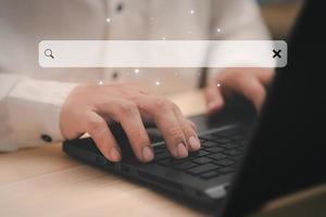 Businessman's hand working with computer laptop on desk in home. Searching Browsing Internet Data Information with blank search bar. Search Engine Optimization SEO Networking Concept. photo