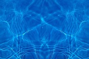 Defocus blurred transparent blue colored clear calm water surface texture with splashes and bubbles. Trendy abstract nature background. Water waves in sunlight with copy space. Blue watercolor shining photo