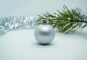 Christmas ball, tinsel and Christmas tree branch. Silver Christmas ball, tinsel and Christmas tree branch on a white background. photo