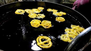 Jalebi indio freír en un cárter de aceite en el establo foto