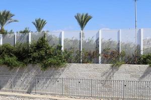 Green plants and flowers grow along the fence. photo