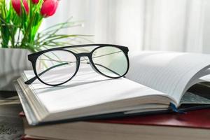 gafas de lectura puestas en un libro abierto al lado de la ventana foto