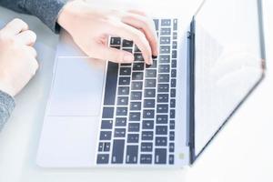 Woman working at home office using laptop searching web, browsing information photo