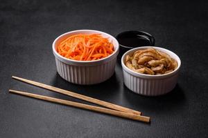 Tasty spicy Korean carrot with spices and herbs on a dark concrete background photo