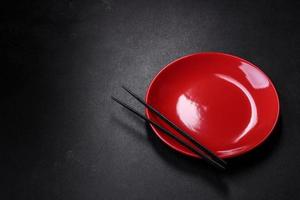 Empty plate with wooden sticks for Asian food on a dark concrete background photo