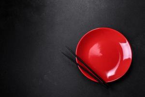 Empty plate with wooden sticks for Asian food on a dark concrete background photo