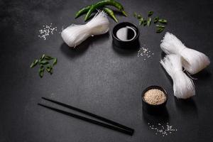 Tasty dish of Asian cuisine with rice noodles, chicken, asparagus, pepper, sesame seeds and soy sauce photo