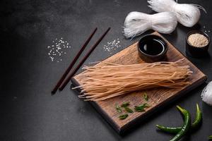 Tasty dish of Asian cuisine with rice noodles, chicken, asparagus, pepper, sesame seeds and soy sauce photo