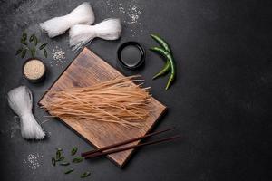 Tasty dish of Asian cuisine with rice noodles, chicken, asparagus, pepper, sesame seeds and soy sauce photo