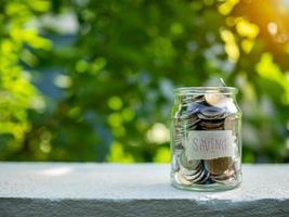 Coins in glass bottles on nature background. The concept of savings and investment. photo