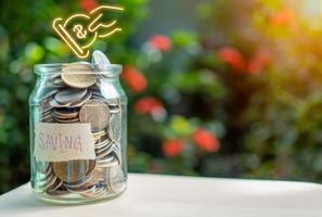 Coins in glass bottles on nature background. The concept of savings and investment. photo