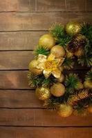 Shiny yellow Christmas balls and cone with barks and pine branches on brown wooden boards background. New year card photo