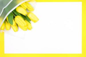 Holiday card. Bouquet of yellow tulips in wrapper with blank sheet for text. Happy birthday, mother's, teacher, International Women's Day, March 8. Copy space photo