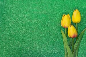 tres tulipanes amarillos sobre fondo verde con destellos. tarjeta de felicitación con pascua, 8 de marzo, feliz cumpleaños, día de la madre. copie el espacio foto