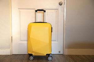 Yellow travel suitcase in the bedroom on the door background - relaxing time, holidays, weekend and traveling concept. photo