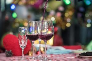 Pouring red wine into glasses in Christmas celebration, Hands holding the glasses of champagne and wine making a toast with copy space. photo