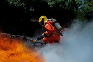 entrenamiento de rescate de bomberos para detener la llama ardiente, el bombero usa casco y traje de uniforme de seguridad para protección contra quemaduras usando hacha para romper un automóvil para rescatar al conductor y los pasajeros atrapados. foto