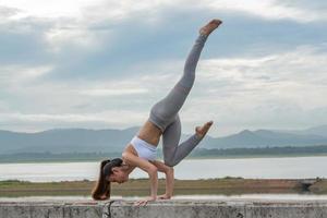 Young Asian woman doing Yoga exercise in beautiful lake with mountain background in the morning. photo