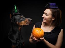 Portrait of a Doberman dog with a girl owner. In carnival costumes with a pumpkin. photo