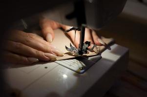 The woman is sewing with sewing machine. Sewing is one of the oldest of the textile arts. photo