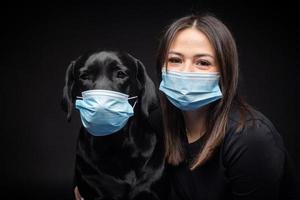 Portrait of a Labrador Retriever dog in a protective medical mask with a female owner. photo