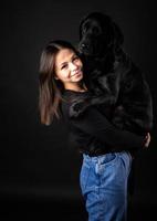 una niña sostiene un perro labrador en sus brazos. foto