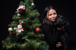 retrato de un perro labrador con su dueño, cerca del árbol verde de año nuevo. foto