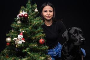 retrato de un perro labrador con su dueño, cerca del árbol verde de año nuevo. foto