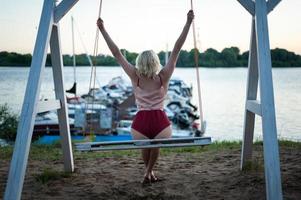 the concept of dreams and happiness, a romantic beautiful carefree woman relaxing on a swing on the beach. photo