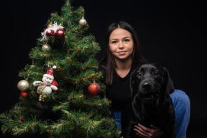 retrato de un perro labrador con su dueño, cerca del árbol verde de año nuevo. foto