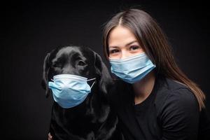 Portrait of a Labrador Retriever dog in a protective medical mask with a female owner. photo