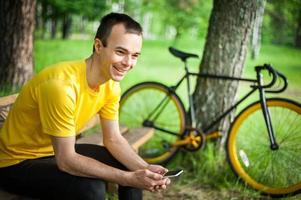 A young man sitting on a bench in a public Park communicates via mobile communication. photo