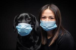 Portrait of a Labrador Retriever dog in a protective medical mask with a female owner. photo