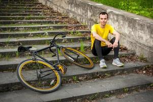 un joven se detuvo a descansar con su bicicleta en un parque público. foto
