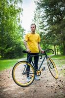 un joven se detuvo a descansar con su bicicleta en un parque público. foto