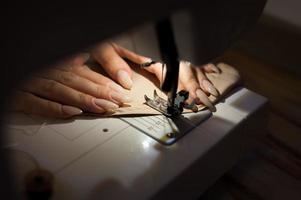 The woman is sewing with sewing machine. Sewing is one of the oldest of the textile arts. photo