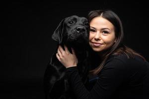 A girl holds a Labrador Retriever dog in her arms. photo