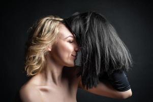 a young blonde woman with a wig, holding a black wig in her hand. on black background photo