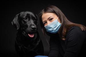 Portrait of a Labrador Retriever dog in a protective medical mask with a female owner. photo