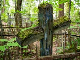 An old unattended cross covered with green moss. photo